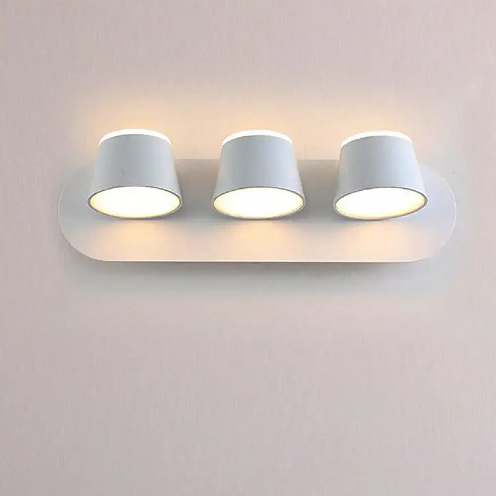 White minimalist metal shade wall sconce with three cylindrical led bulbs and compact fixture width for bedroom vanity