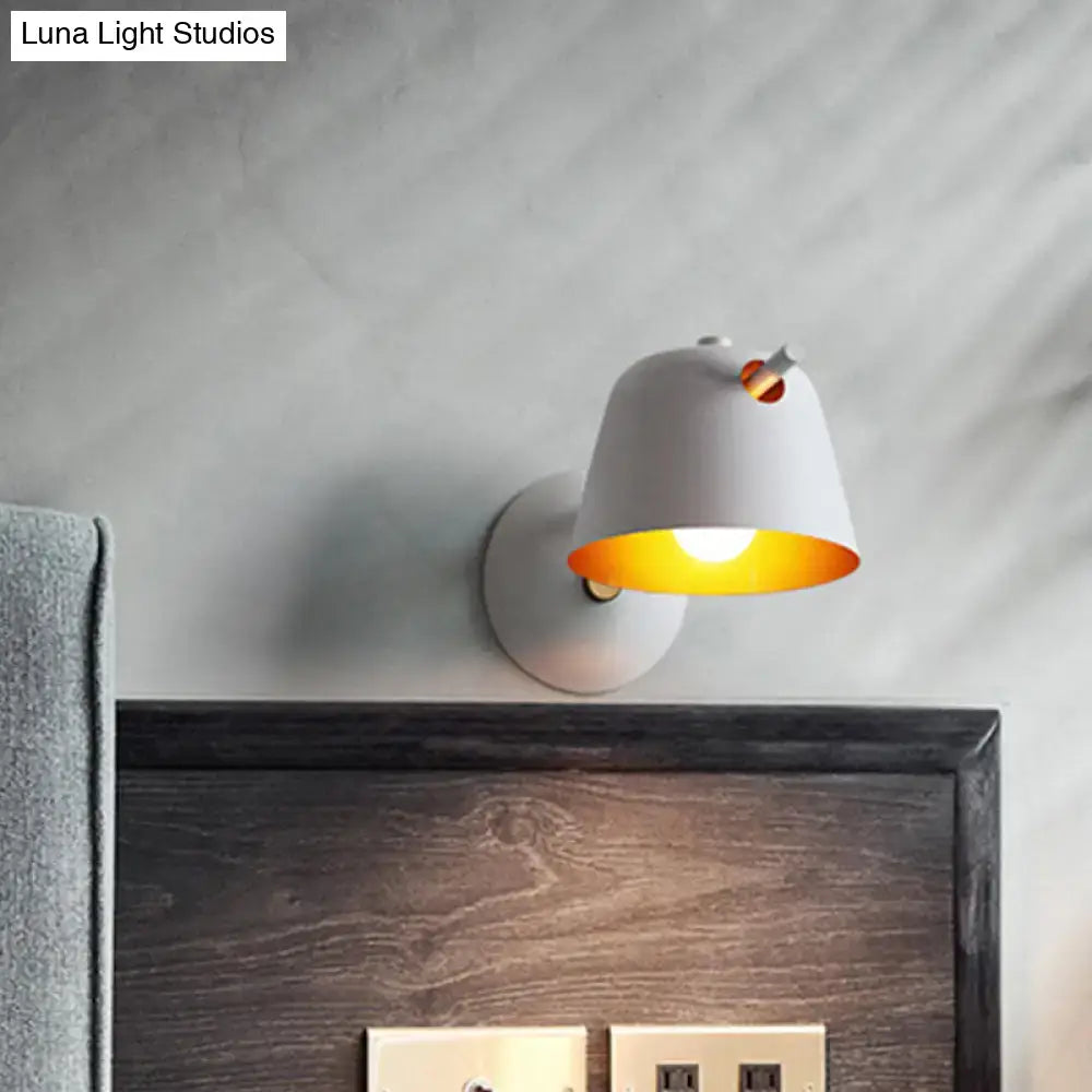 Modern black metal shade wall sconce with white ceramic and warm yellow glow featuring a small orange accent for bedroom use