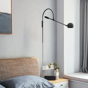 Modern black metal sphere wall sconce with curved arm and direct wired electric design for bedroom lighting
