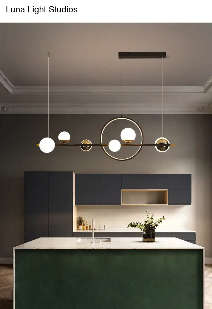 Modern black metal pendant light with spherical glass bulbs and sleek brass frame for dining room lighting