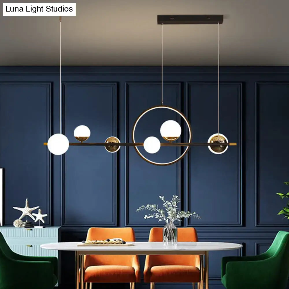 Modern black metal pendant light with gold-toned frame and white spherical glass shades for dining room lighting