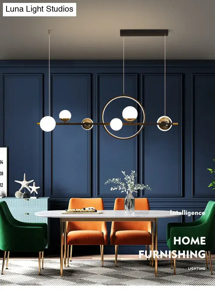 Modern black metal pendant light with sleek brass frame and white spherical glass shades for dining room use