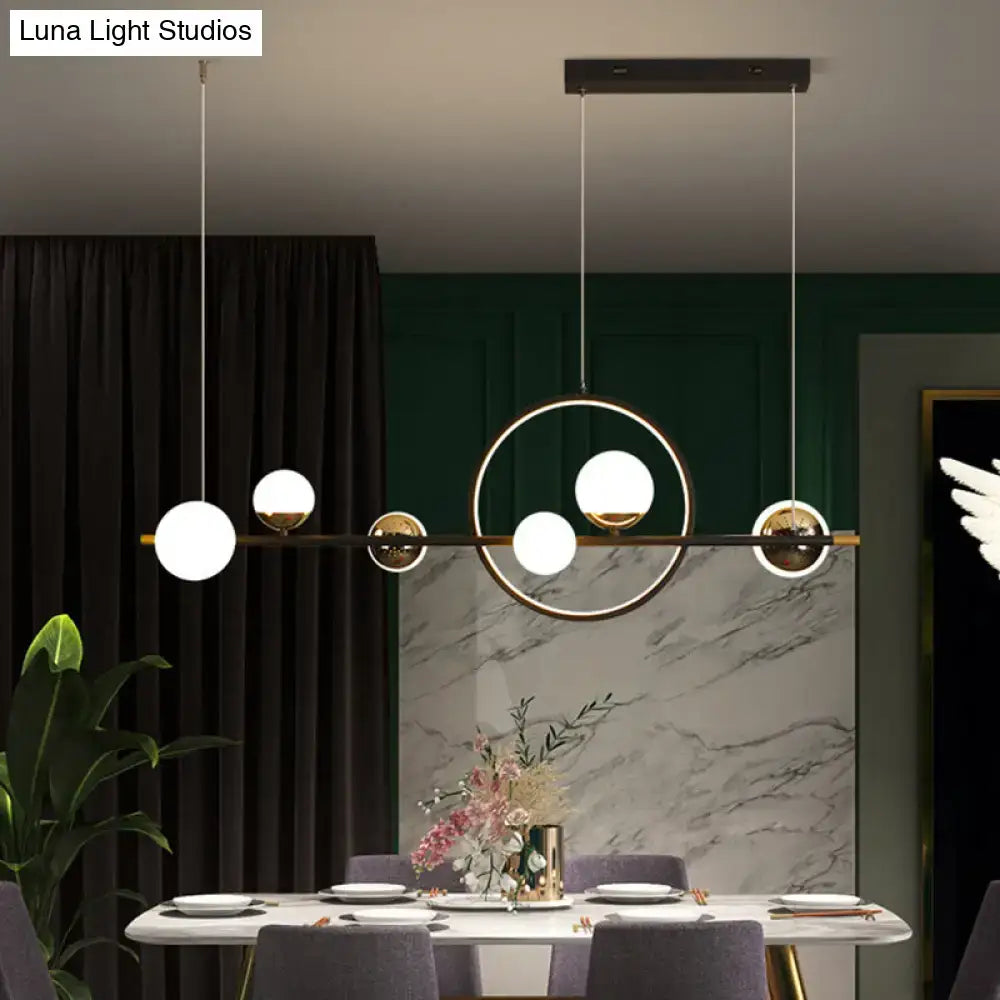 Modern black metal pendant light with gold-toned frame and spherical white glass shades for dining room lighting