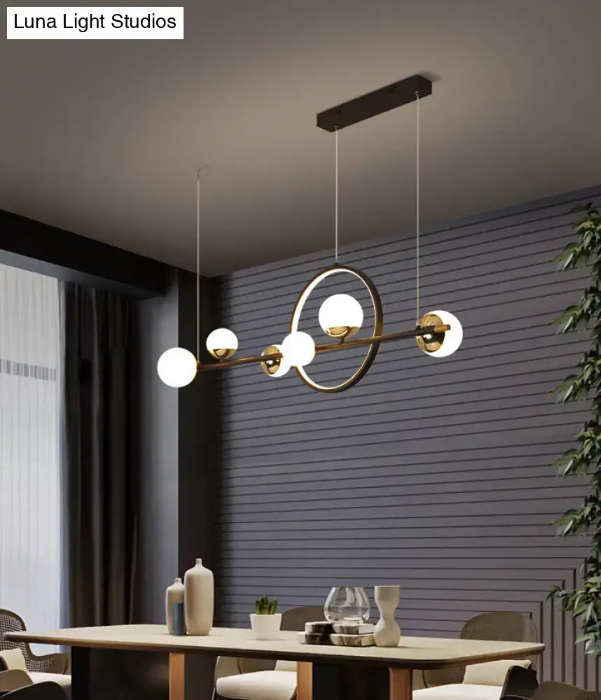 Modern black metal pendant light with brass finish, spherical glass globes, and central circular ring for dining room