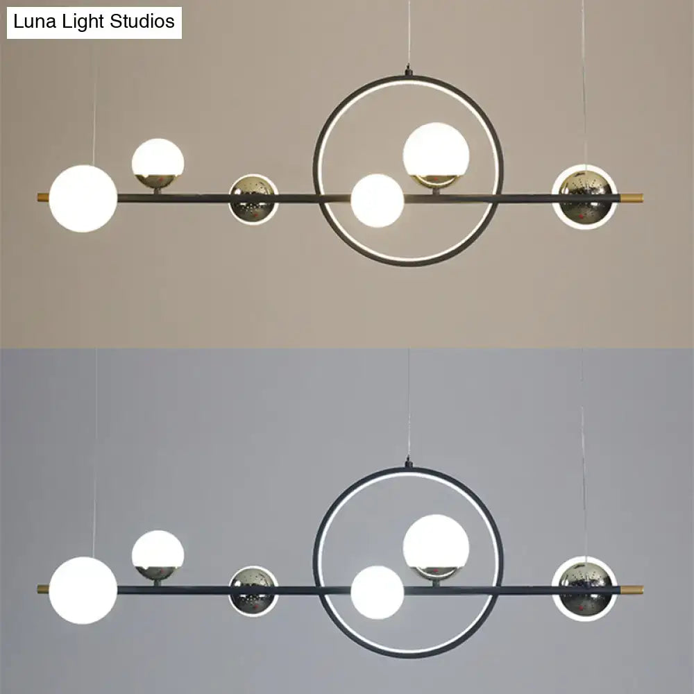 Modern black metal pendant light with brass geometric frame and spherical glass bulbs for dining room use