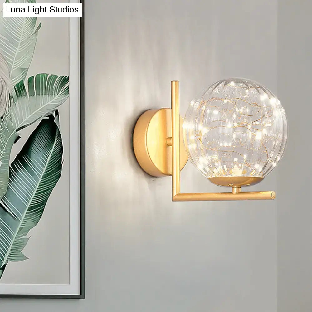 Gold-toned mini globe wall sconce with clear textured glass globe and delicate fairy light fixture height ideal for bedroom