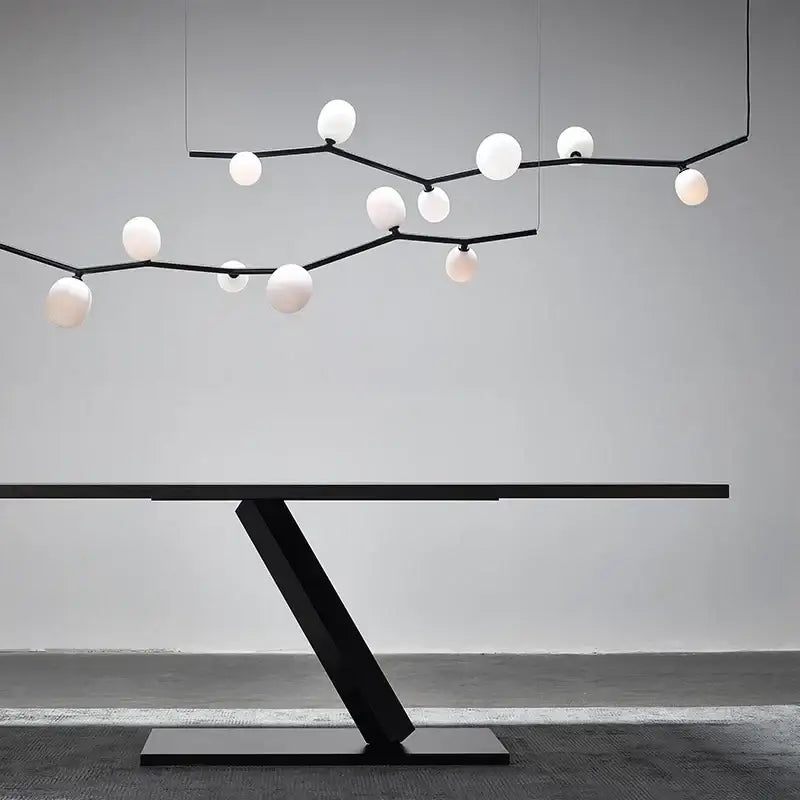 Modern black minimalist glass branch chandelier above a sleek black metal table with angular base for dining room decorbites glass branch