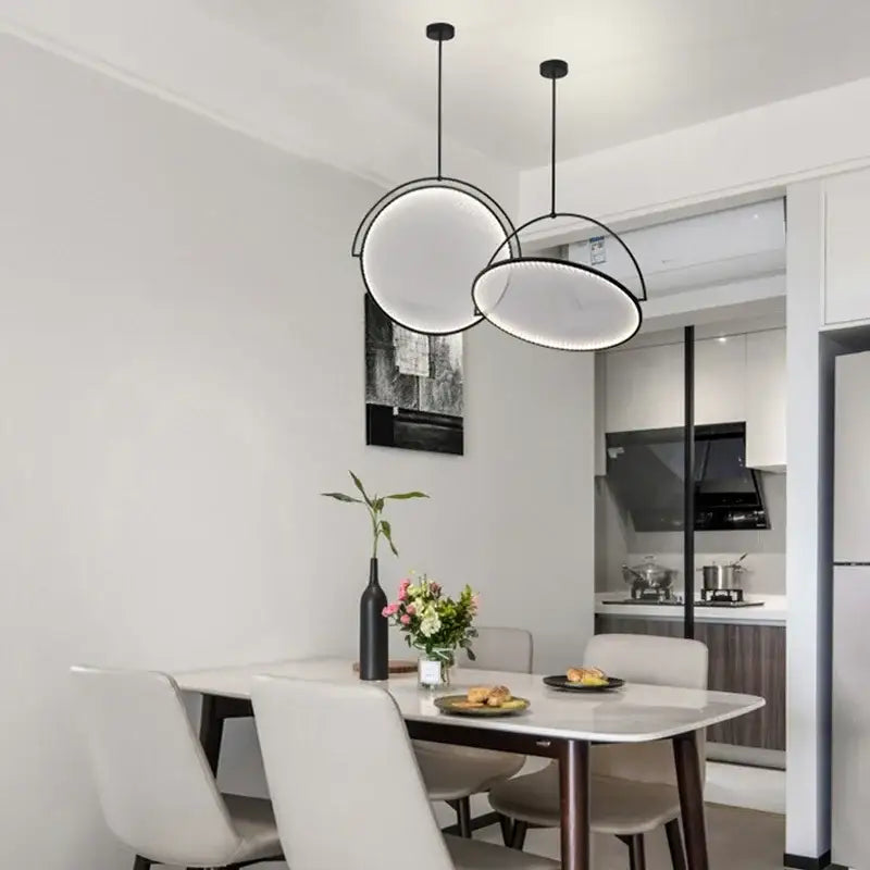 Modern black minimalist led pendant light with circular black frames and glowing white interiors above dining table
