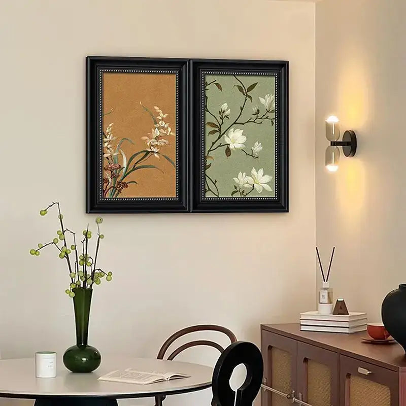 Modern black-framed decorative painting with white blossoms on green and beige electric meter box cover panel
