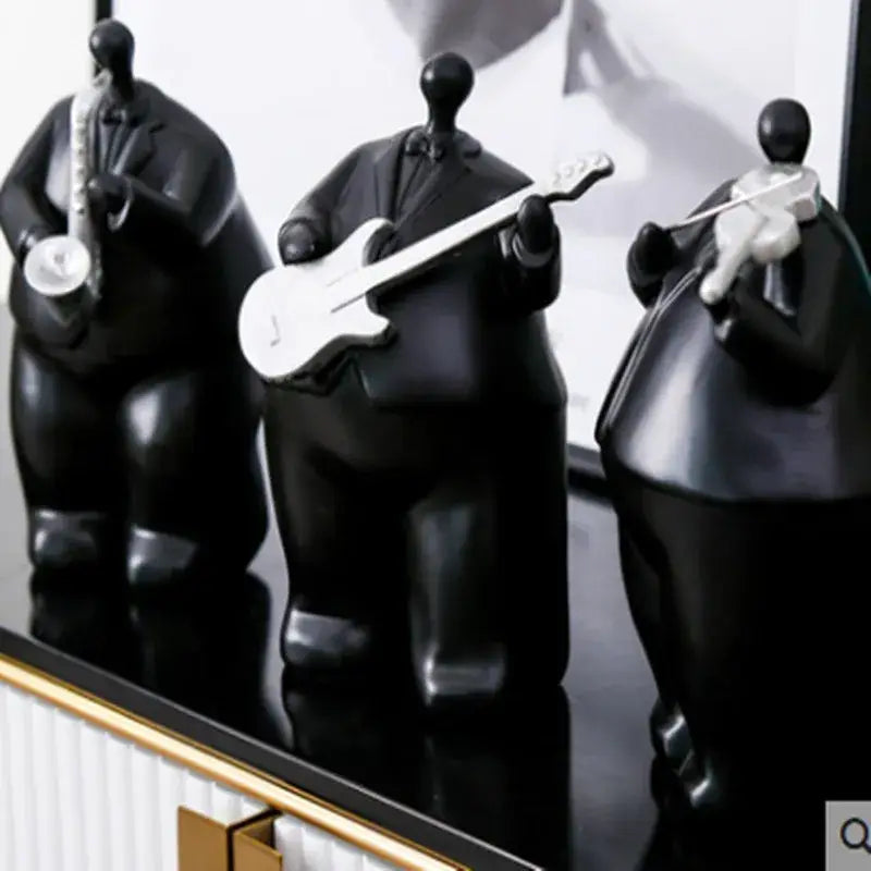 Three glossy black musical instrument band figurines in suits holding white saxophone guitar and violin for decor