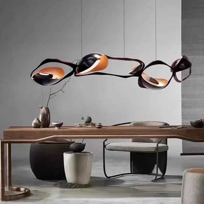 Modern black and orange abstract glass pendant light with painted iron details suspended above wooden dining table selected version