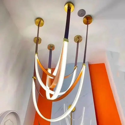Modern pendant light featuring curved glowing white and orange led strips with gold fixtures for modern interiors