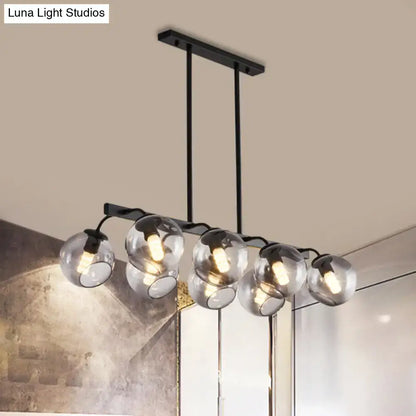 Modern black metal chandelier with five clear glass globe shades featuring a black orb shade for kitchen and dining room