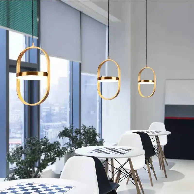 Three modern black oval adjustable angle pendant lights with gold frames and illuminated bands for dining room decorbites