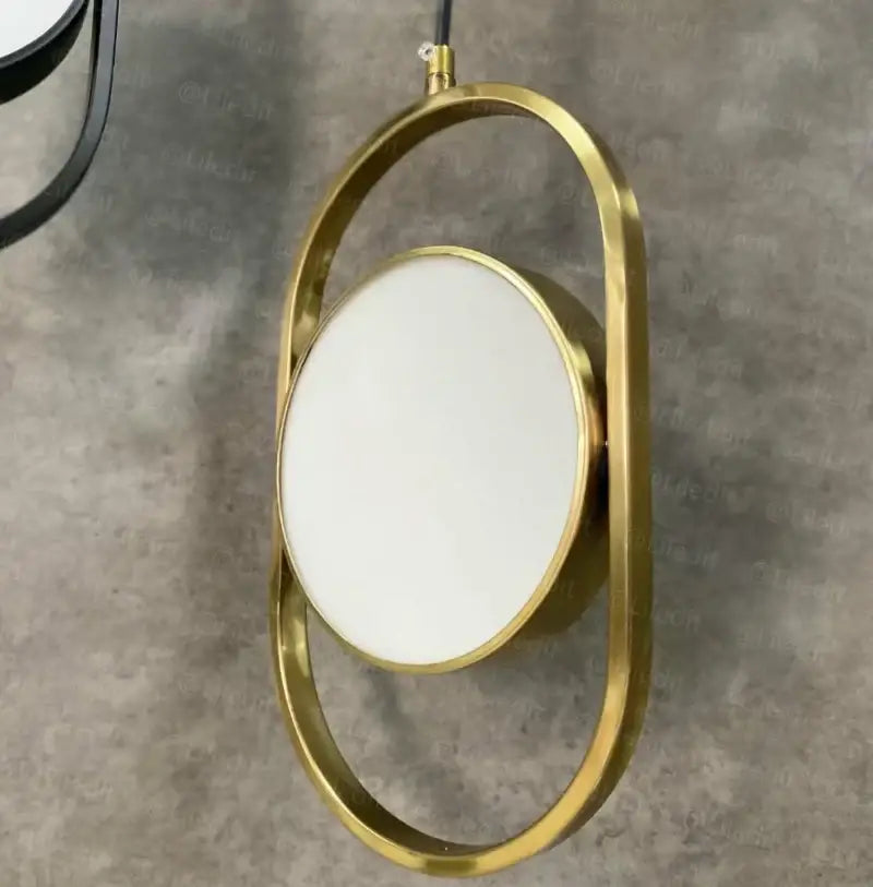 Gold-framed oval mirror with sleek modern design paired with modern black decorbites adjustable angle pendant light