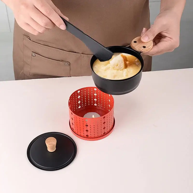 Modern black ceramic raclette fondue set with wooden handle and lid on red perforated stand for heat distribution