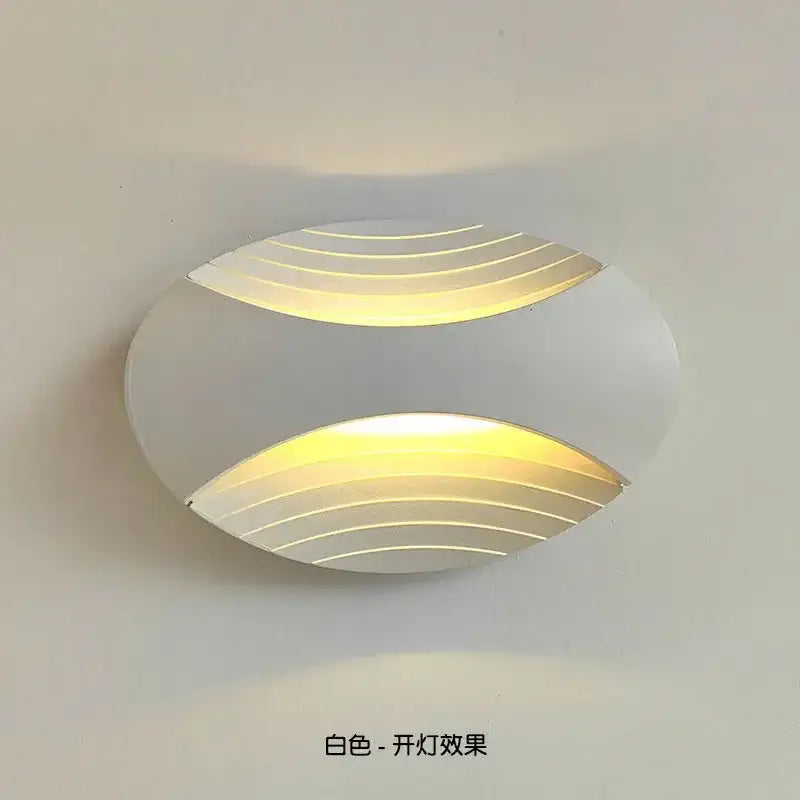 White oval wall lamp with curved illuminated horizontal lines casting warm yellow glow for modern corridor lighting