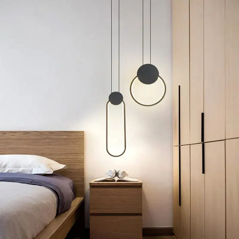 Modern black ring pendant lamp with gold geometric minimalist design hanging above wooden nightstand decorbites black ring