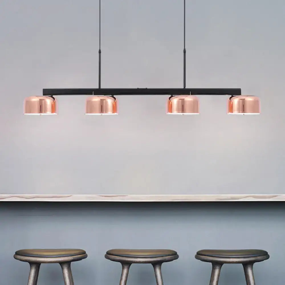 Modern black rose gold diner island lamp with copper finish and four cylindrical lampshades on sleek black bar