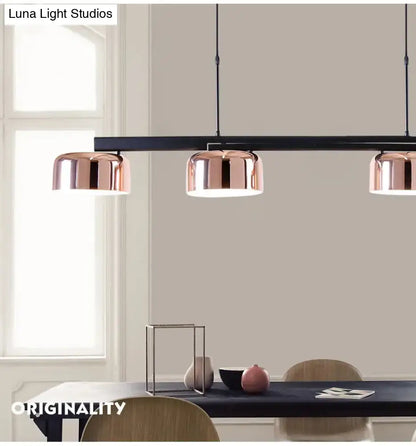 Modern black rose gold diner island lamp featuring three copper-finished dome pendant lights on a black bar
