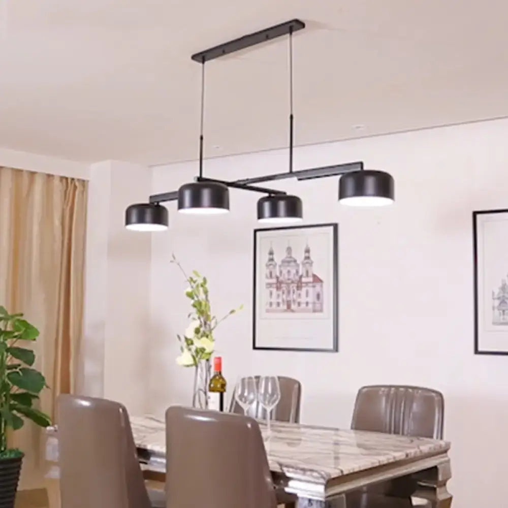 Modern black rose gold diner island lamp with four cylindrical shades suspended from a rectangular bar pendant light