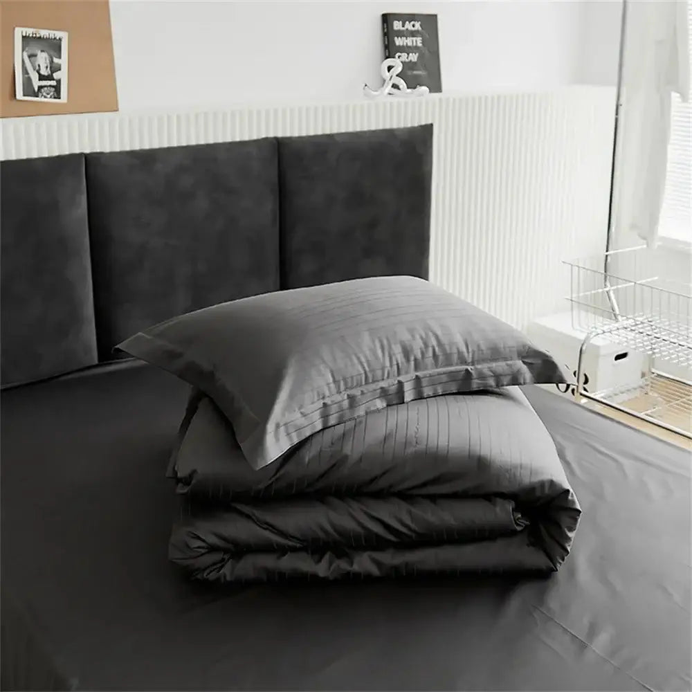Modern black satin jacquard duvet cover set with dark gray striped duvet cover and matching pillowcases neatly folded on bed