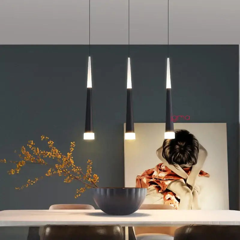 Three sleek modern black and silver conical tube pendant lights with white illuminated tips hang above a kitchen island