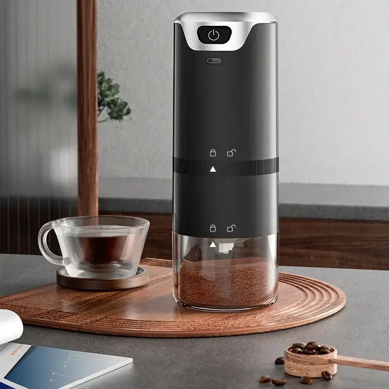 Modern black and silver electric coffee tamper barista grinder with transparent base filled with ground beans for espresso use