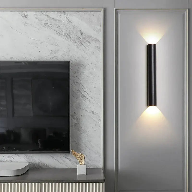 Modern black cylindrical led wall lamp with silver accents and warm up and down lighting for bedroom use