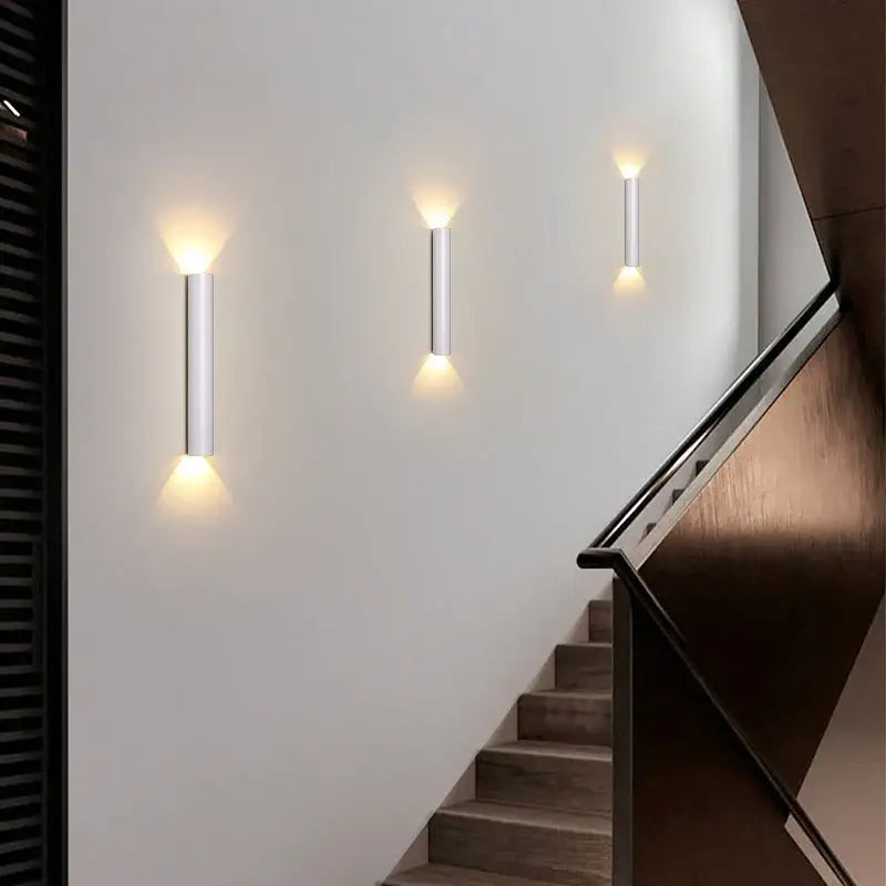 Three sleek black and silver led wall lamps with brushed metallic finish emit warm light for bedroom or tv background