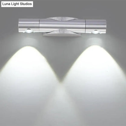 Silver metallic wall-mounted light fixture with two adjustable spotlights providing warm white lighting for living room
