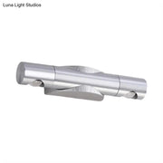 Silver metallic wall-mounted light fixture with two cylindrical arms and warm white lighting for living room use