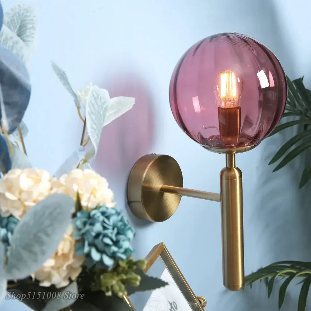 A sleek brass wall lamp with a textured mauve decorbites glass ball led globe and exposed filament bulb for bedroom decor
