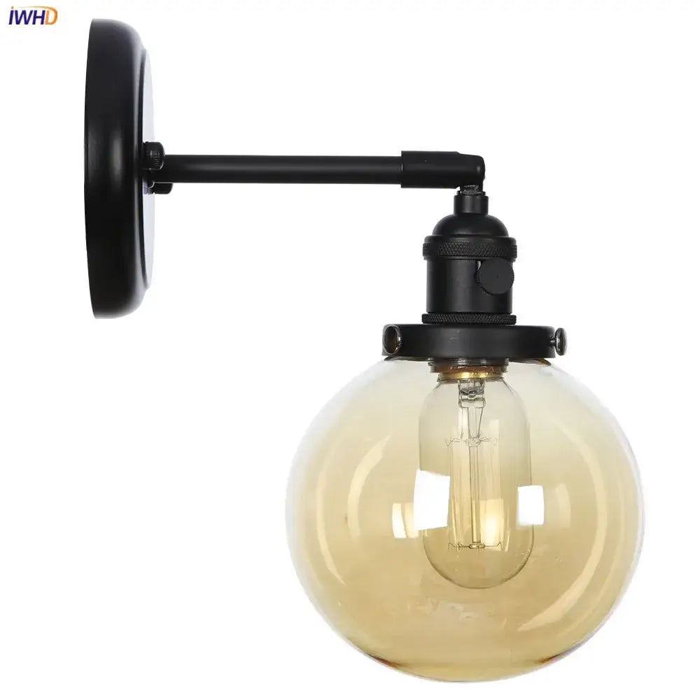 Modern black metal wall sconce with a spherical amber decorbites glass ball and exposed filament bulb for hallway lighting