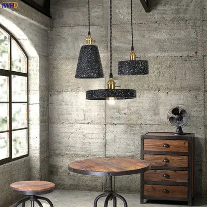 Three black speckled decorbites cement pendant lamps with brass accents hang from twisted cords for kitchen lighting