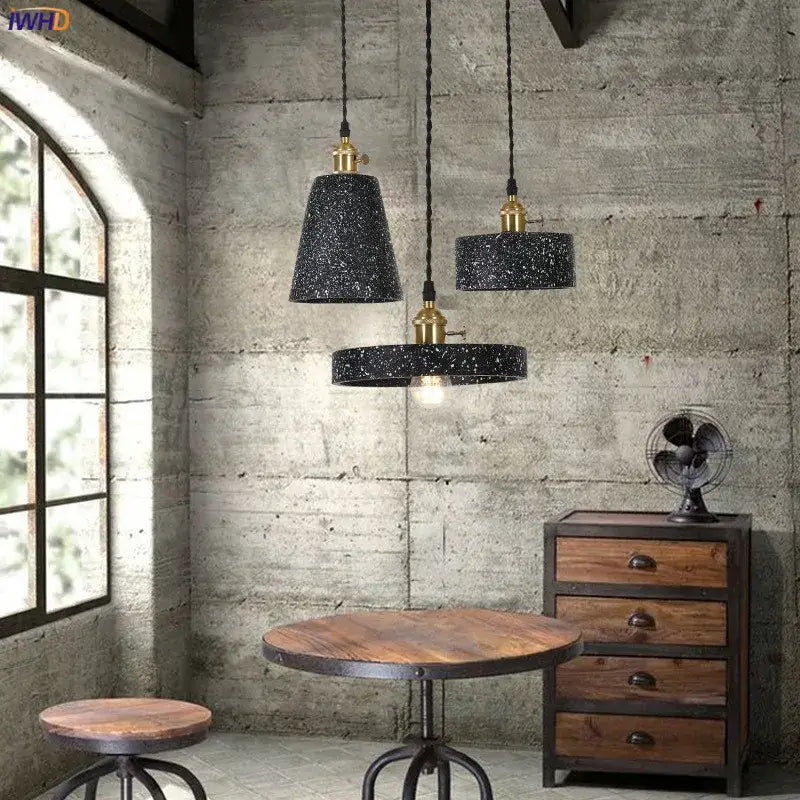 Three black speckled decorbites cement pendant lamps with brass accents hang from twisted cords for kitchen lighting