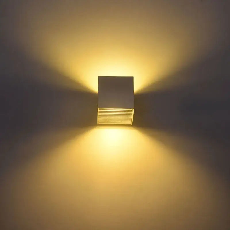 Modern black square 12w cob led wall lamp with matte white and brushed metallic design emitting warm yellow light