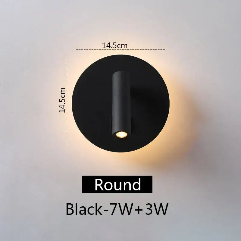 Modern black round led wall lamp with sleek cylindrical light fixture emitting warm illumination for bedroom reading