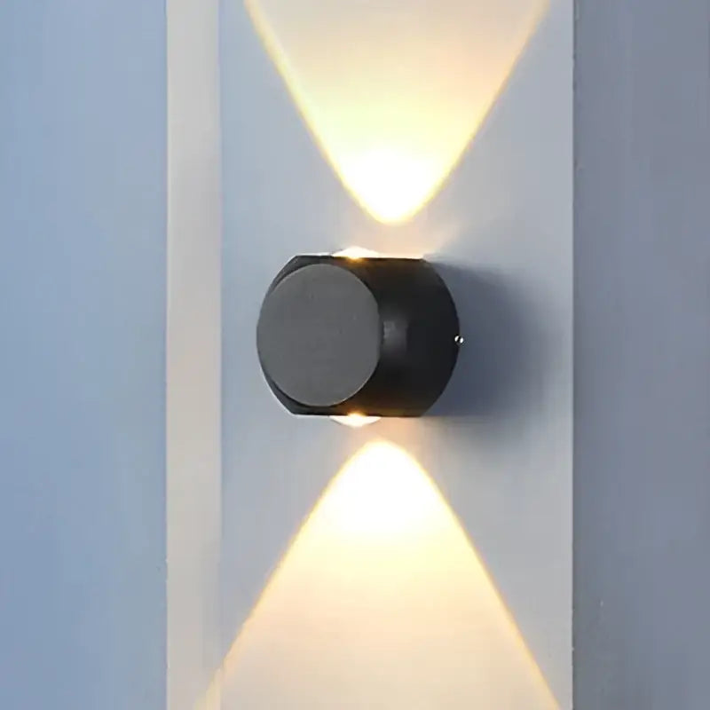 Modern black cylindrical led wall light with two angled lights casting warm beams for outdoor garden decor