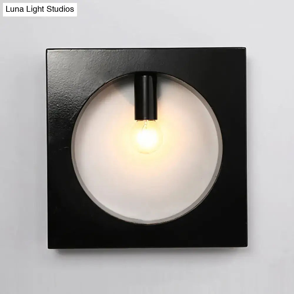 Black square wall sconce lamp with circular frosted glass diffuser and exposed bulb for modern bathroom lighting