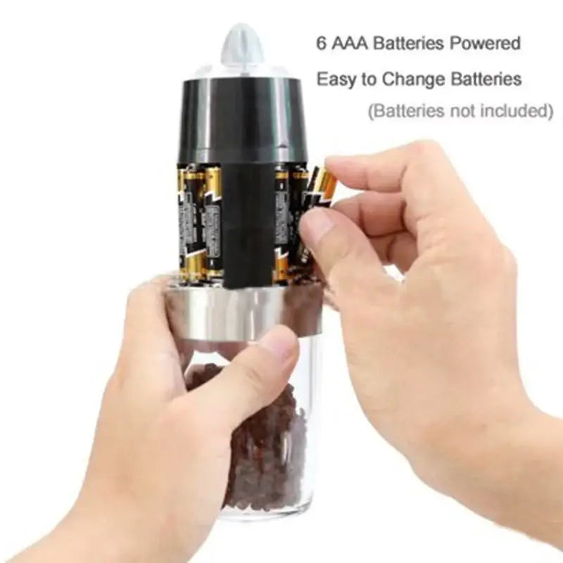 A sleek transparent glass electric salt pepper grinder with black and stainless steel motorized top housing six aaa batteries