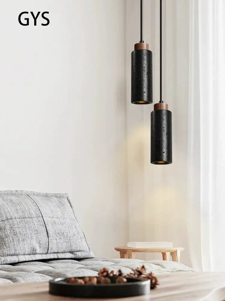 Modern black stone bedside chandelier featuring black cylindrical pendant lights with textured matte finish and wooden accents