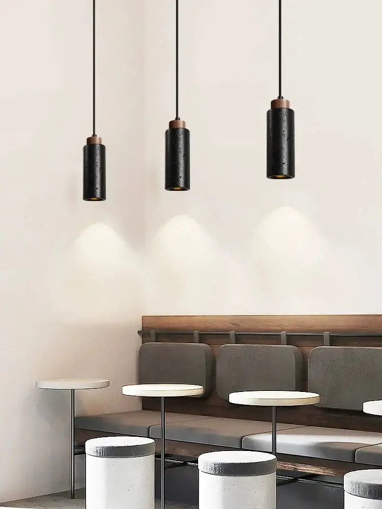 Modern black stone bedside chandelier featuring three sleek black cylindrical pendant lights with copper accents