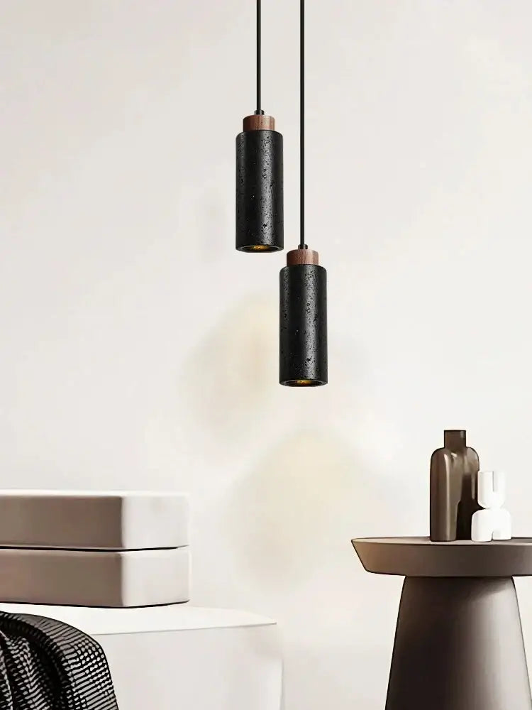 Modern black stone bedside chandelier with sleek black cylindrical pendant lights and warm wooden accents by decorbites