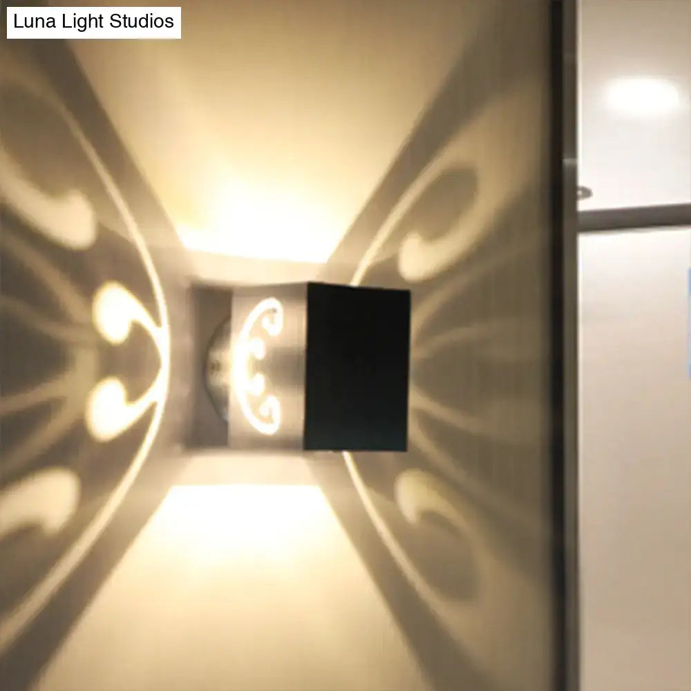 Modern black led wall lamp with ornate swirl design casting warm light patterns for bedroom use