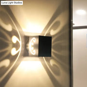 Modern black led wall lamp with ornate swirl design casting warm light patterns for bedroom use