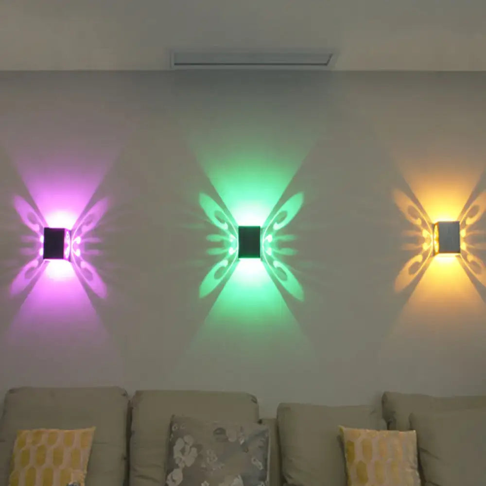 Three modern black swirl led wall lamps shaped like butterflies emitting vibrant purple green and yellow light