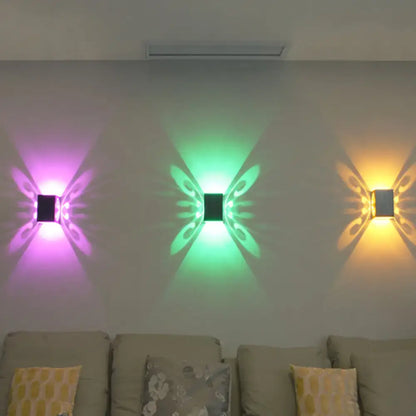 Three modern black swirl led wall lamps shaped like butterflies emitting vibrant purple green and yellow light