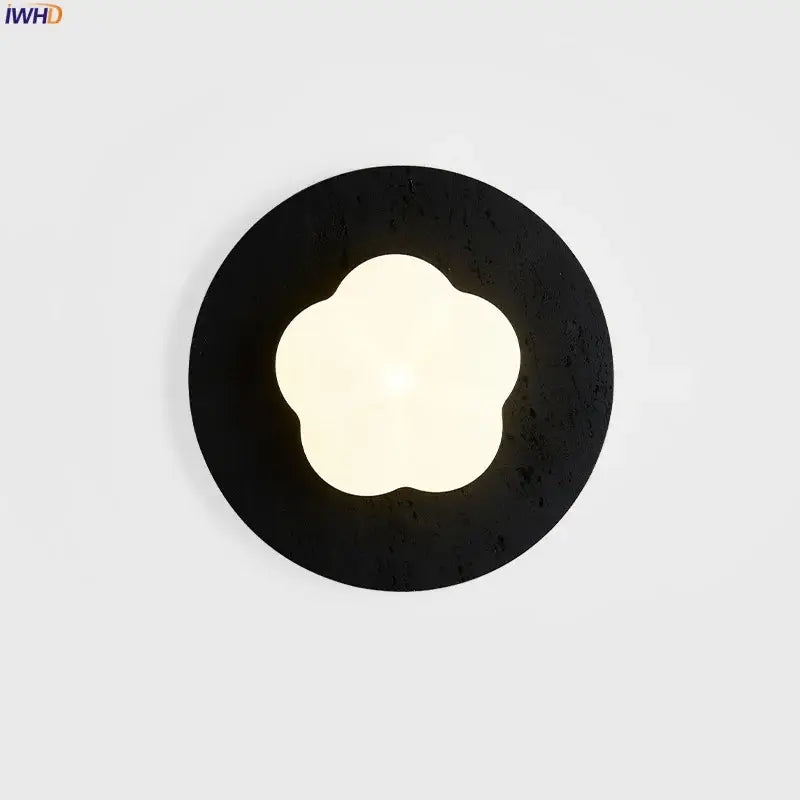 Modern black travertine wall lights with textured circular sconce and glowing four-petal flower led center by decorbites