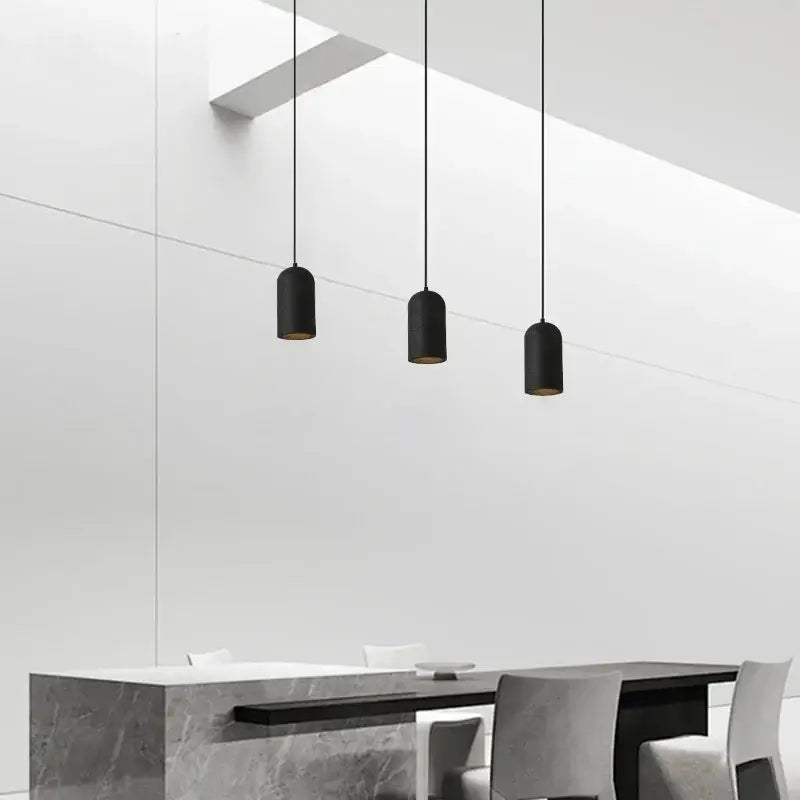 Three sleek black travertine led pendant lamps with gold interior lining hang from ceiling in modern kitchen decorbites style